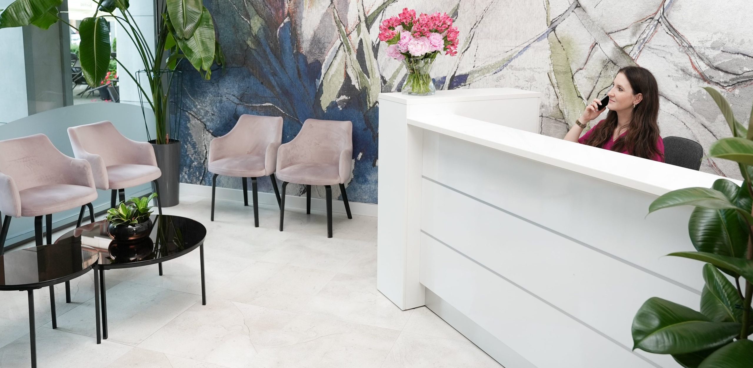 Recepcja FEBUMED Metro Dworzec Gdański - uśmiechnięta recepcjonistka rejestruje pacjenta przez telefon.