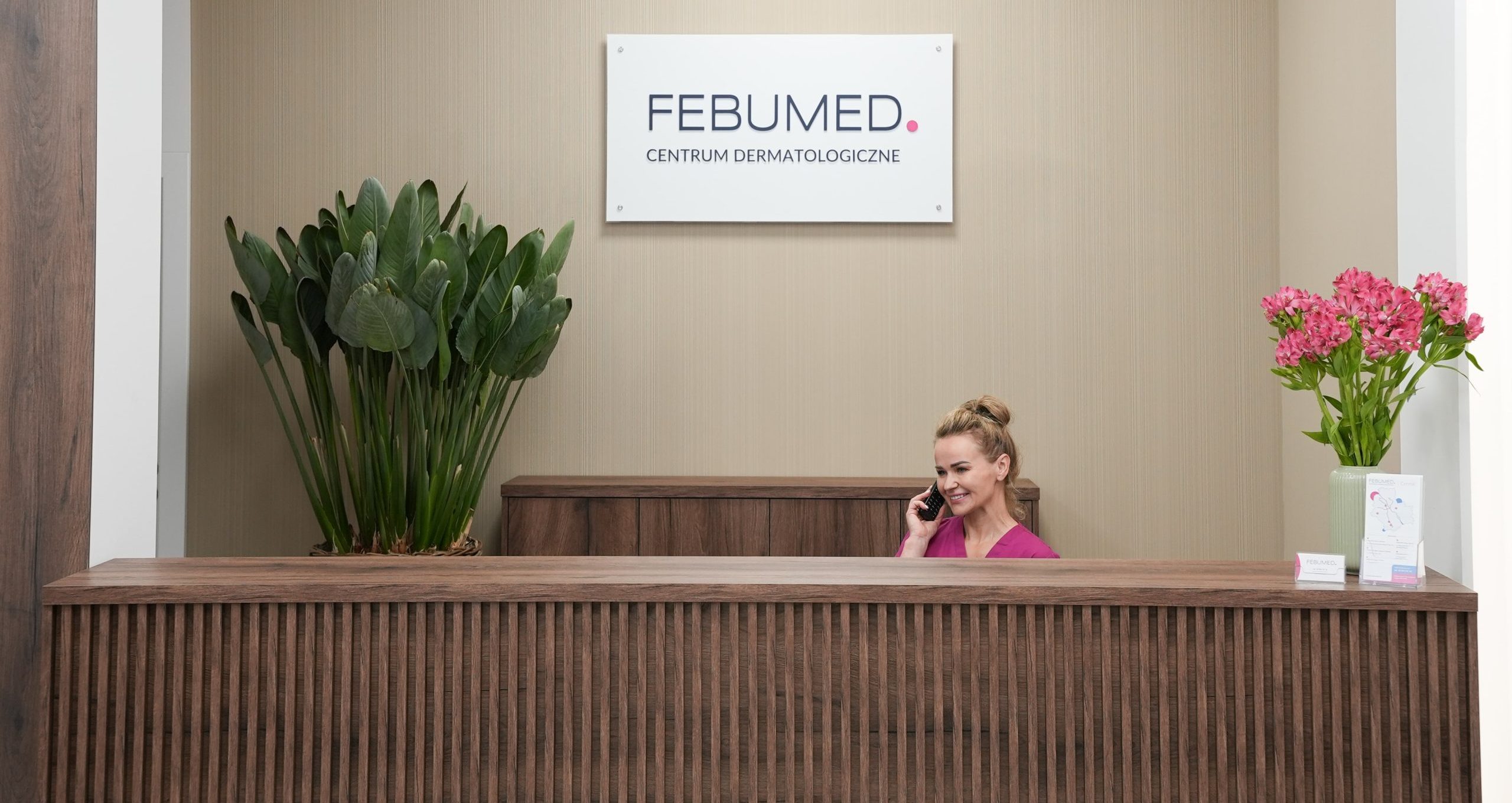 Recepcja w FEBUMED Praga Południe - designerska brązowa lada i rejestratorka umawiająca pacjentów telefonicznie.