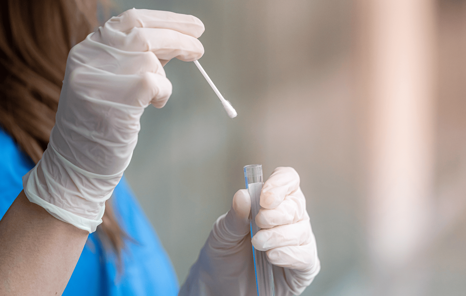 pielęgniarka wkłada wymazówkę do probówki laboratoryjnej