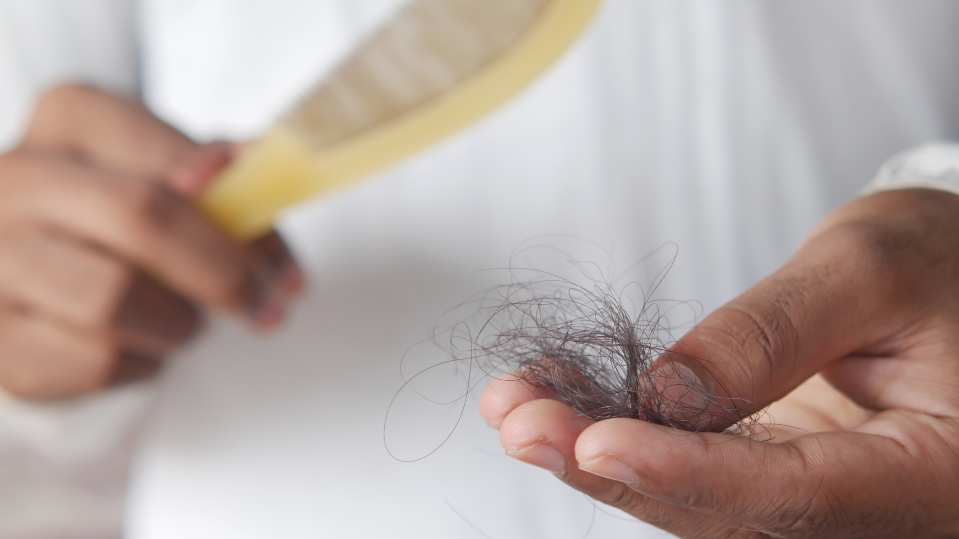 mężczyzna trzymający w ręku kłębek włosów zdjęty z grzebienia po czesaniu głowy