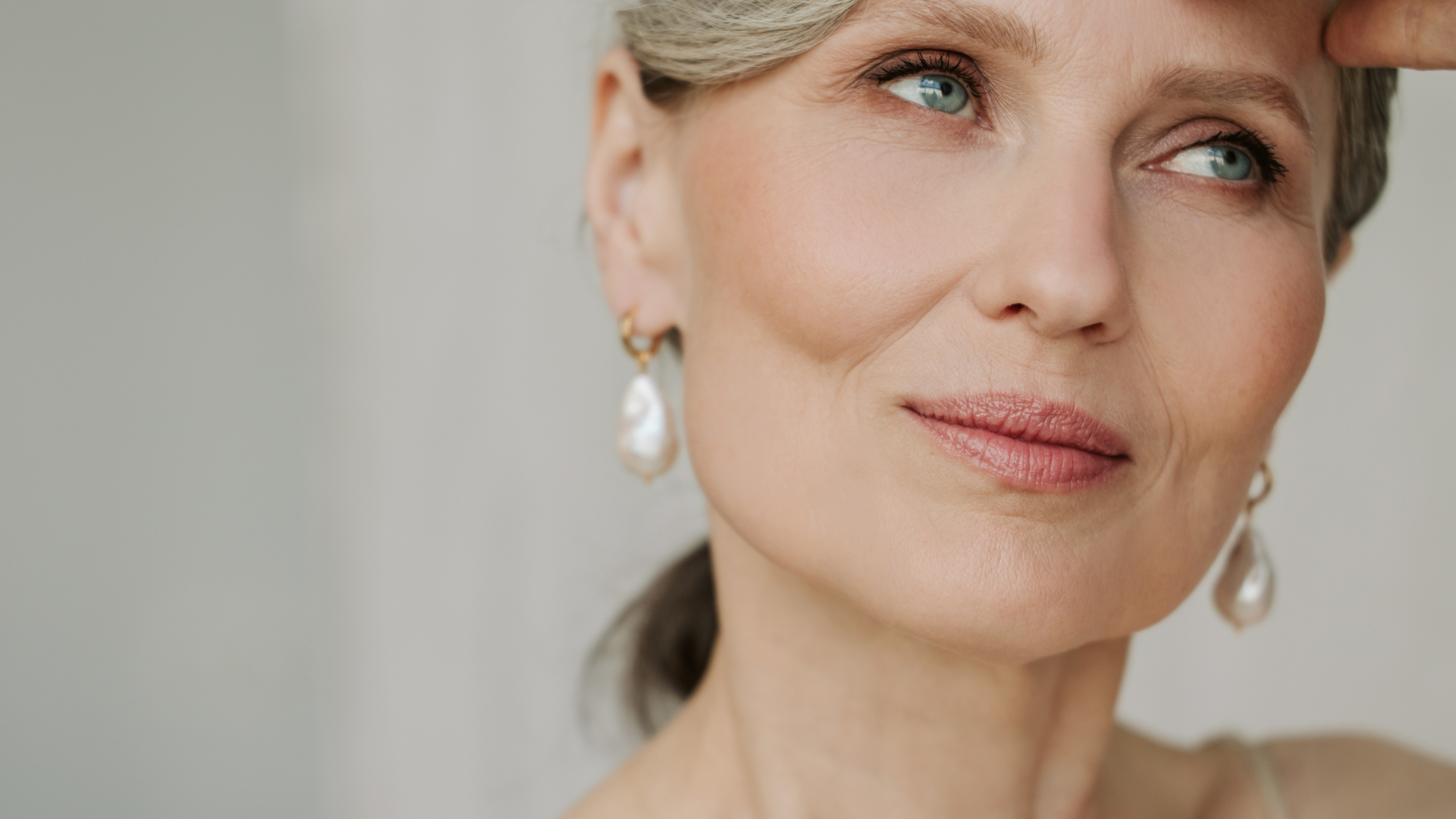 subtelnie uśmiechnięta kobieta z lekko siwymi włosami i widocznymi kośćmi jarzmowymi i kośćmi żuchwy