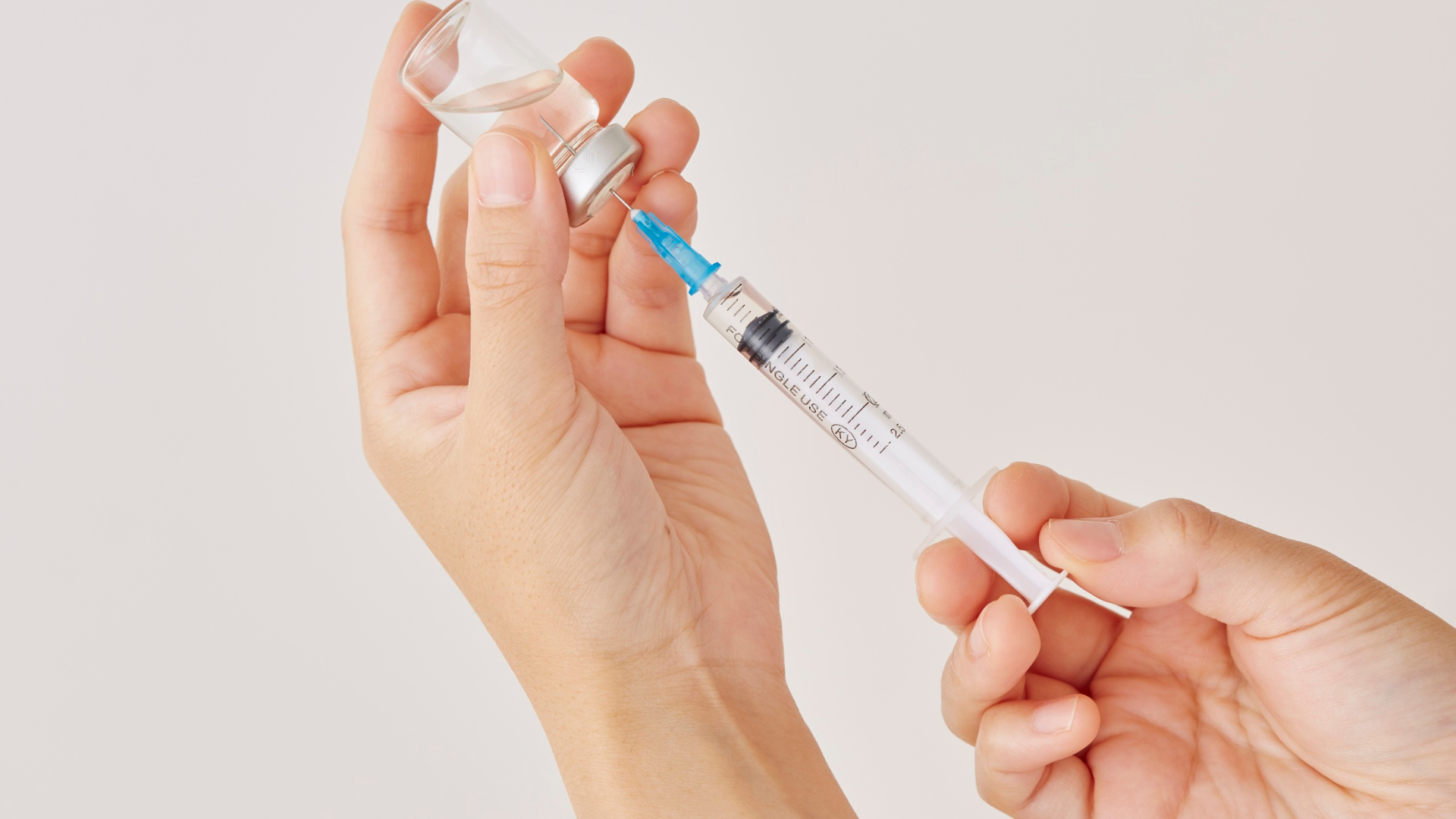 ręce trzymające fiolkę z substancją do mezoterapii, z której pobierana jest jego wskazana ilość.