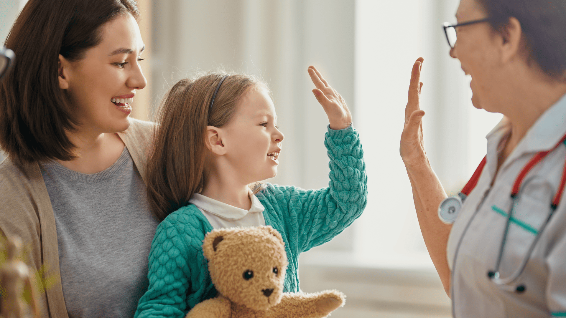 radosna dziewczynka na kolanach u mamy przybija piątkę z uśmiechniętą lekarką