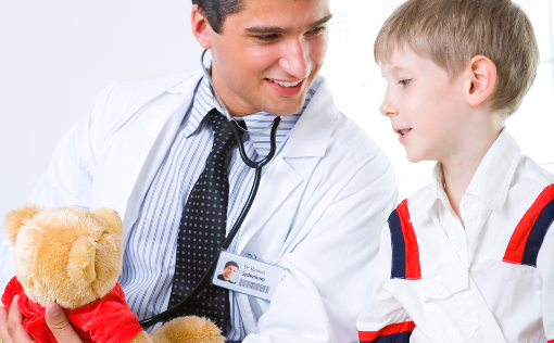 Chirurg dziecięcy rozmawia z dzieckiem i wyjaśnia procedurę na pluszowym misiu