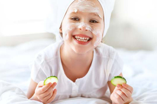 Uśmiechnięte dziecko z kremem na policzku - skuteczna pielęgnacja skóry z AZS.